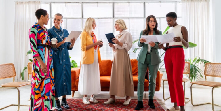 Diverse Group of Women in Colorful Outfits Talking and Smiling Inside a Senior Living Facility