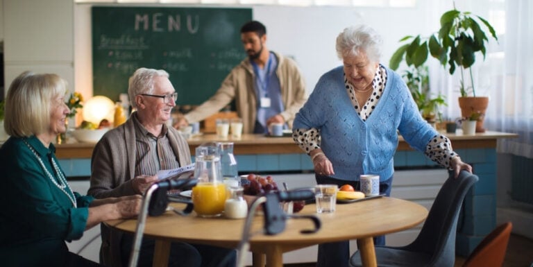 Elderly Residents Enjoying Breakfast Together in Dining Area at Memory Care Facility